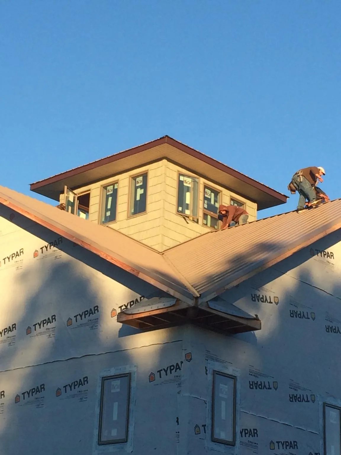 Roofers working around a rooftop cupola on a new metal roof at sunset — Roof Waterproofing in Arlington by Roofing Brothers